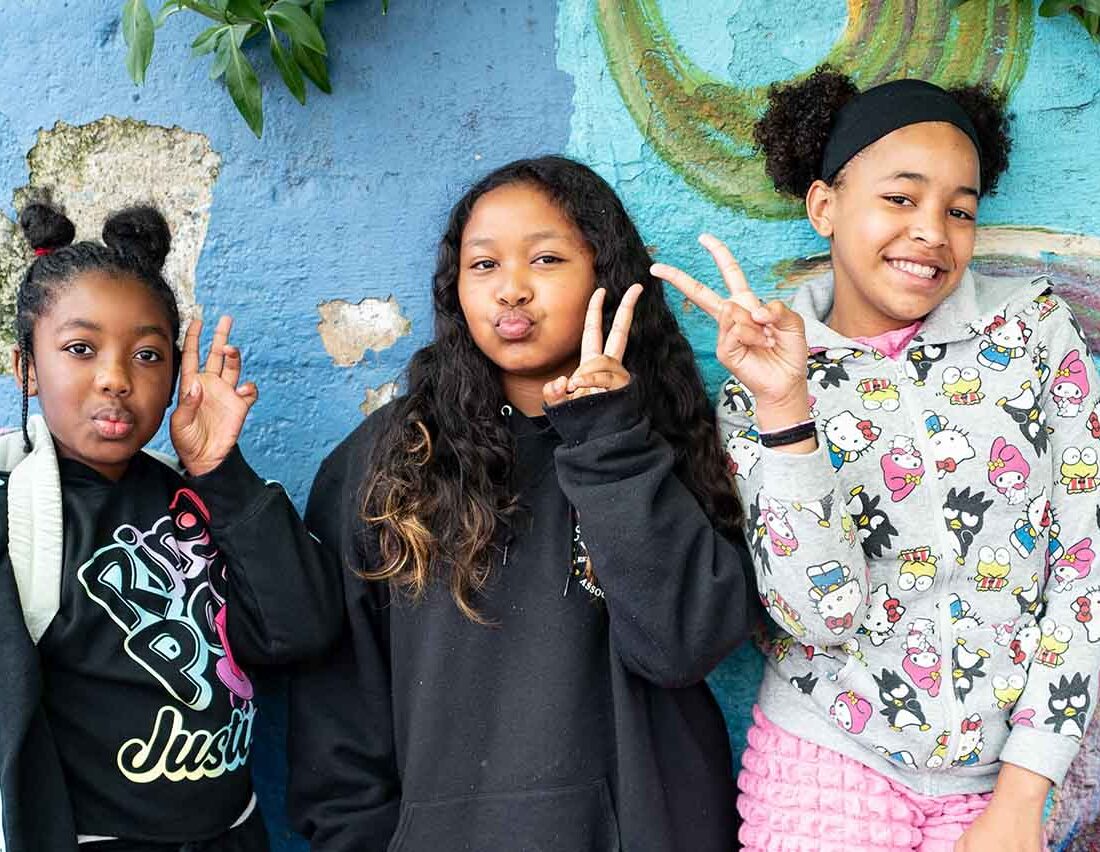 Three 5th grade students smile and pose with peace signs